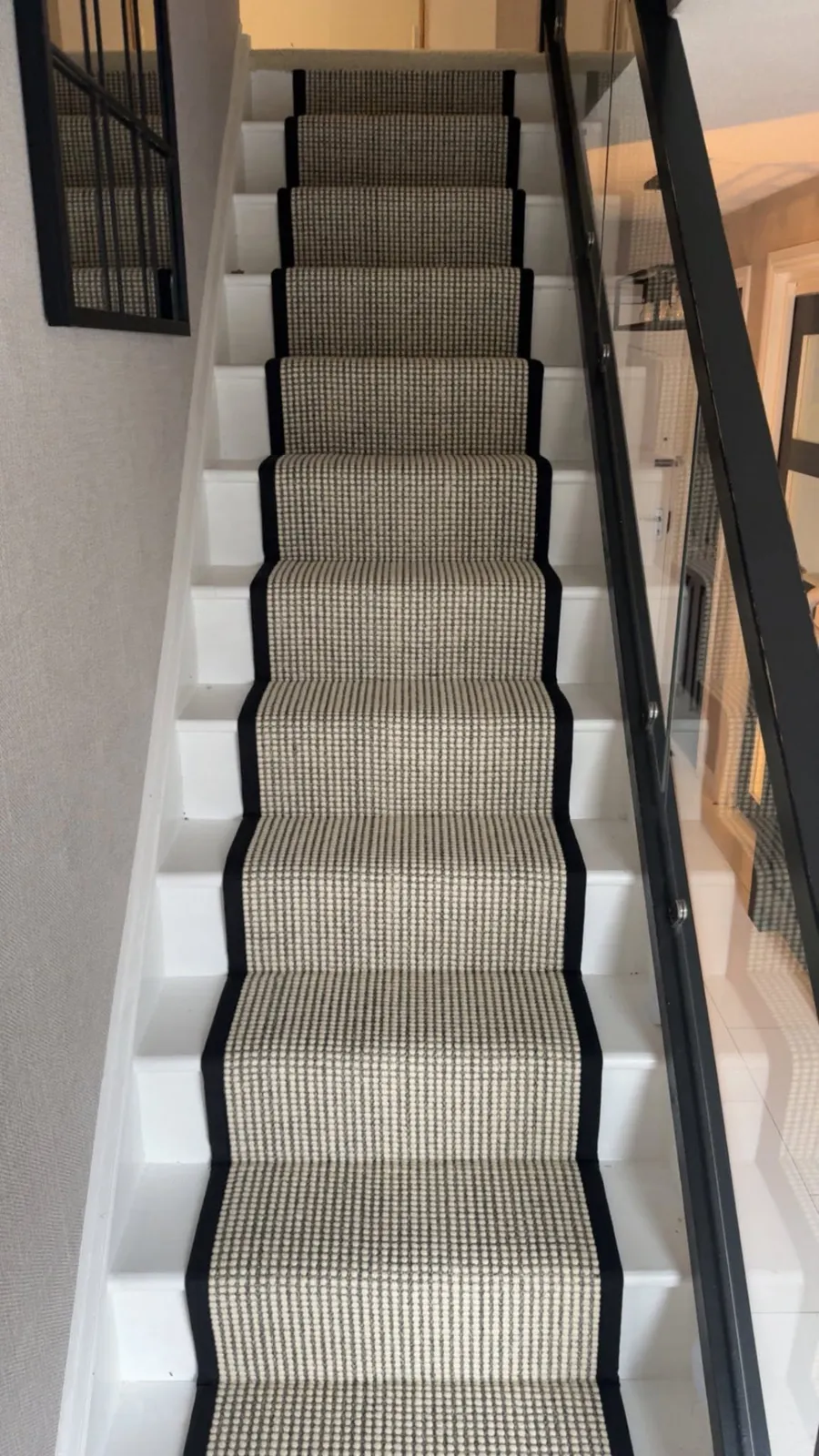 Textured neutral stair runner with black contrasting edging on white painted stairs