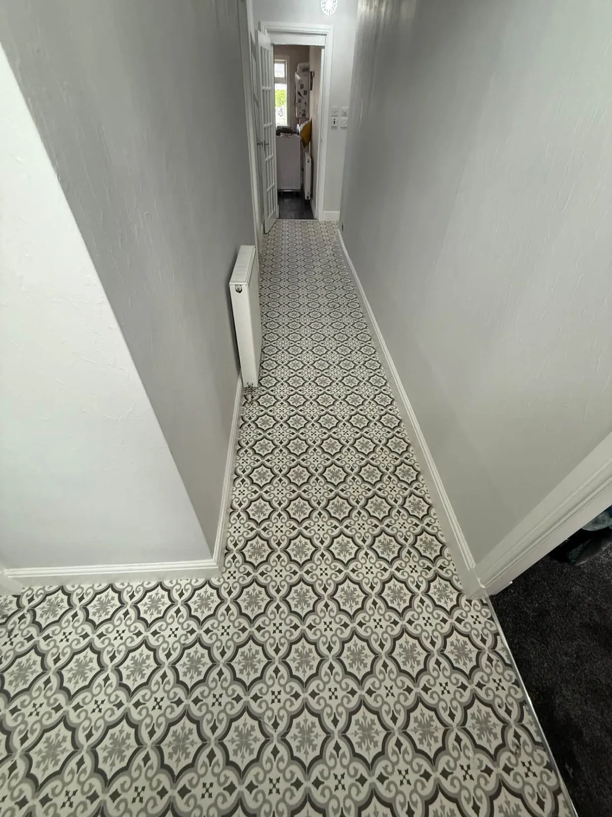 Grey and white patterned tile-effect floor fitted along a long hallway
