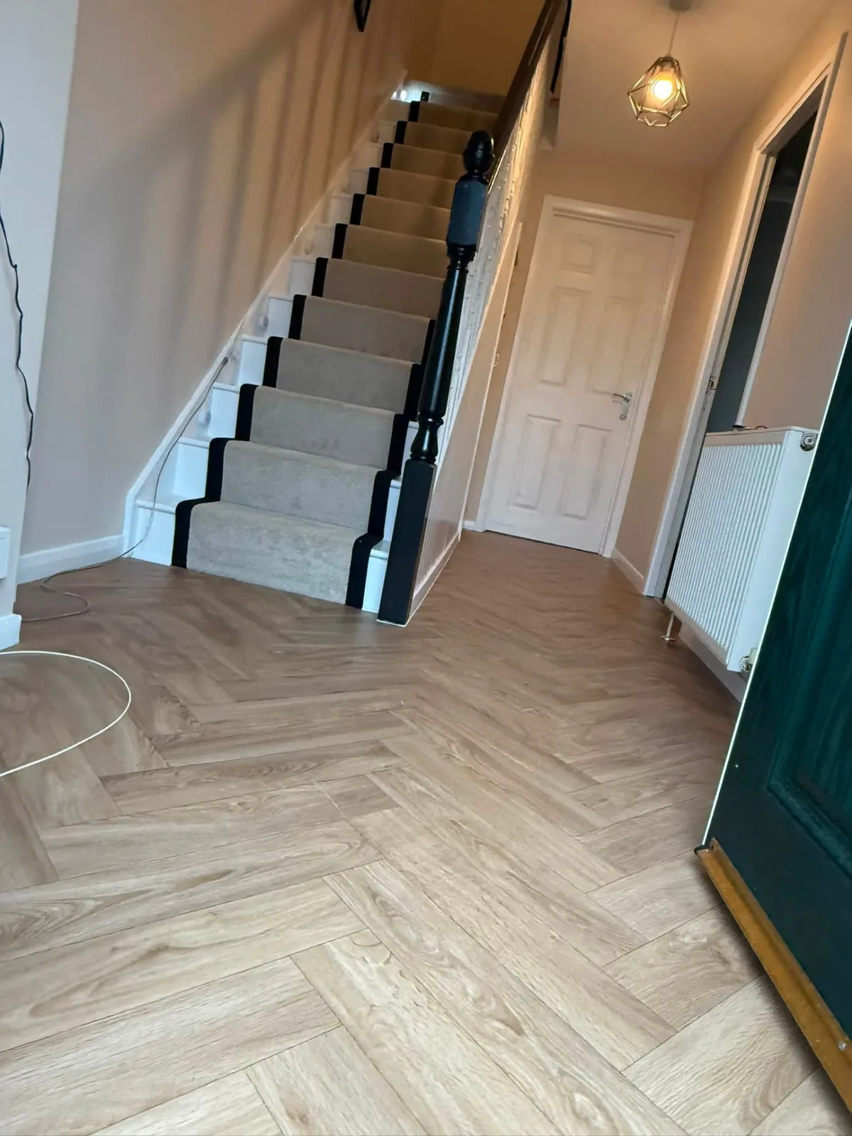 Hallway with herringbone wood-effect floor and a carpet stair runner with black edging